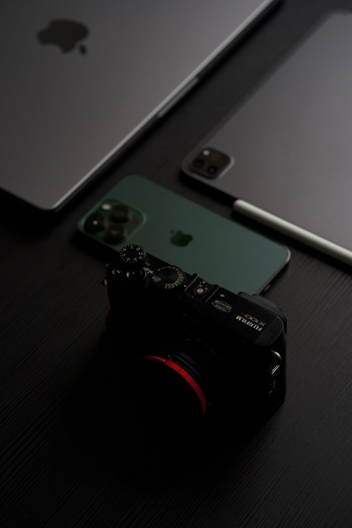 A vertical shot showcasing modern electronics including a smartphone, tablet, laptop, and camera.